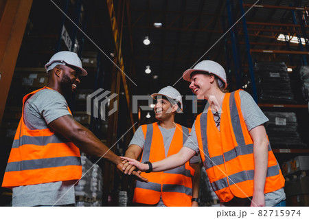 A Group of Diversity warehouse workers giving hand for high-five after success the project and celebrating together in a distribution center warehouse. 82715974
