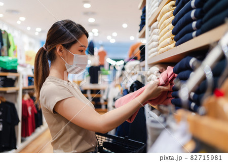 Asian woman wearing a protective face mask buying cloth in store 82715981