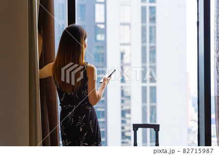 Portrait rear view of woman standing close to the window in hotel room after check-in 82715987