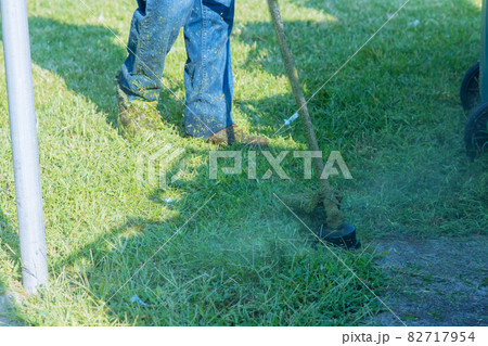 A utility worker in a green lawn with a lawn cutting grass A utility worker in a green lawn with a lawn cutting grass 82717954