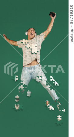 Full-length creative collage of man listening to music in a jump isolated over green background. Portrait consist of puzzle pieces 82719210