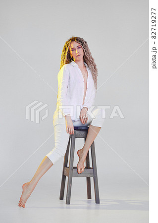 Full length portrait of tender woman in white clothes lighted with violet and yellow lights 82719277
