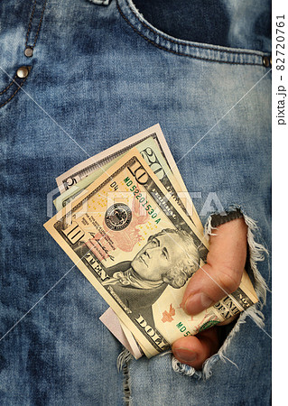 Hand holds US dollar banknotes in jeans rip hole Hand holds US dollar banknotes in jeans rip hole 82720761