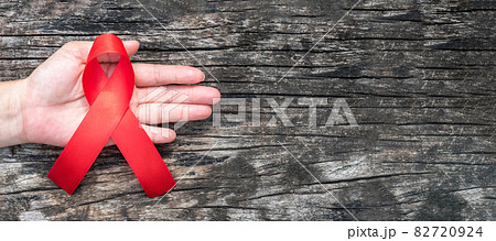 World aids day and national HIV AIDS and ageing awareness month with red ribbon on helping hand (isolated with clipping path on white background) 82720924