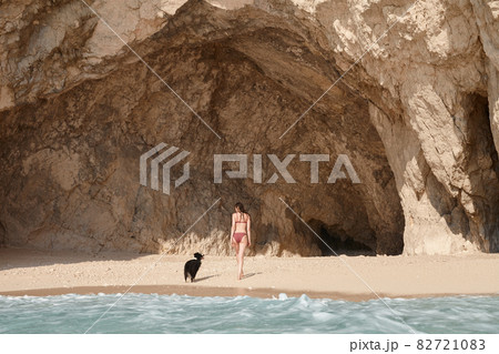 Woman walking on beautiful deserted beach with dog 82721083