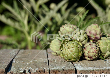 Fresh artichoke globes on wooden table in garden 82721712