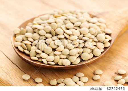 Uncooked lentil on wooden spoon on table. Lens culinaris Uncooked lentil on wooden spoon on table. Lens culinaris 82722476