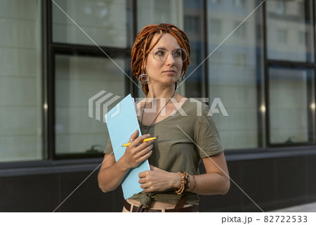 Beautiful girl poses against the background of an office building. Shooting for a business magazine Beautiful girl poses against the background of an office building. Shooting for a business magazine 82722533