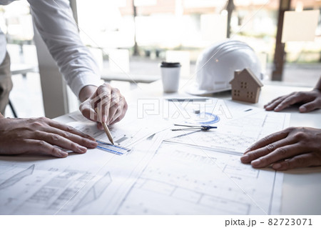 Architects or engineering team consulting and analyzing working on objects tools and construction drawings inspection planning new architectural project on blueprint and model house in modern office 82723071