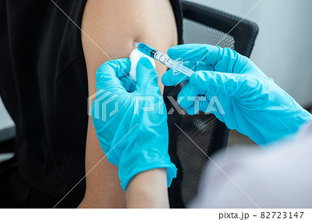 Doctor making a vaccination into patient with needle getting immune vaccine at arm for flu shot, coronavirus protective of epidemic Doctor making a vaccination into patient with needle getting immune vaccine at arm for flu shot, coronavirus protective of epidemic 82723147