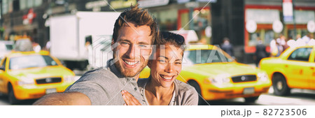 New York selfie couple taking photo on NYC city summer holiday vacation travel with yellow taxi cabs panoramic background. Man and woman tourists happy smiling New York selfie couple taking photo on NYC city summer holiday vacation travel with yellow taxi cabs panoramic background. Man and woman tourists happy smiling 82723506