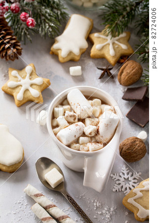 A cup of hot chocolate with marshmallows and gingerbread on a Christmas table. 82724006