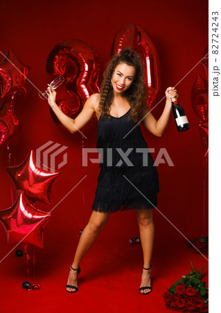 Happy woman with bottle of champagne on red background 82724243