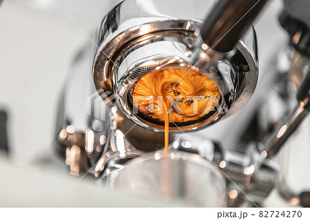 Coffee machine espresso extraction pouring from bottomless naked portafilter. Professional equipment at home or cafe shop. Closeup of brown crema Coffee machine espresso extraction pouring from bottomless naked portafilter. Professional equipment at home or cafe shop. Closeup of brown crema 82724270