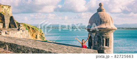 San Juan Puerto Rico travel happy tourist woman waving open arms in happiness at watch tower of Castillo San Felipe del Morro panoramic banner background 82725663