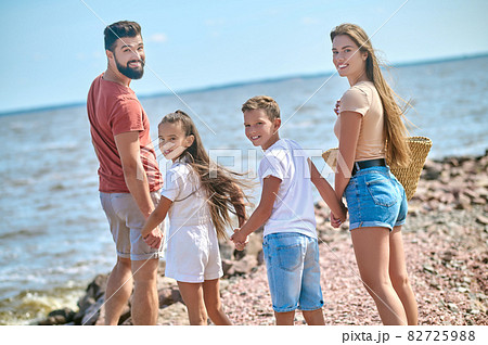 A family walking on a shore holding hands A family walking on a shore holding hands 82725988