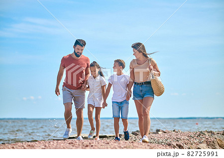 A family walking on a shore holding hands A family walking on a shore holding hands 82725991