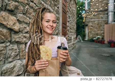 Happy young woman with drink and appetizing snack 82727076
