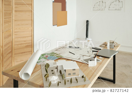 Wooden table with paper house models, sketches and mobile gadgets Wooden table with paper house models, sketches and mobile gadgets 82727142