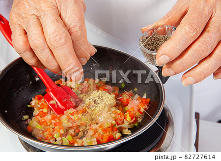 Preparation of the traditional Colombian hogao or criollo sauce (salsa criolla) made of onion, tomato, peppers and cilantro 82727614