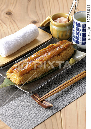 笹の葉に置かれた穴子の姿鮨と壺に入ったガリとお茶とお手拭き 82728811