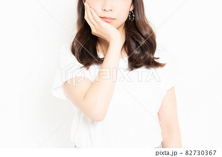 虫歯が痛くて頬に手を当てるTシャツを着ている若い女性 82730367