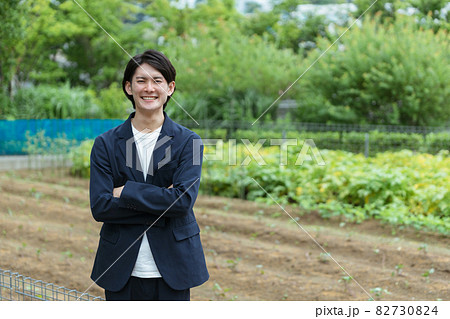 畑で腕組みをする若い男性・新しい農業 82730824