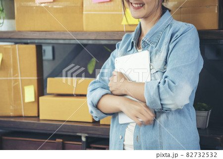 Asian woman startup small business at home office. Online seller entrepreneur young asian woman use tablet checking online order. Woman using tablet check stock goods supply delivery package shipping Asian woman startup small business at home office. Online seller entrepreneur young asian woman use tablet checking online order. Woman using tablet check stock goods supply delivery package shipping 82732532