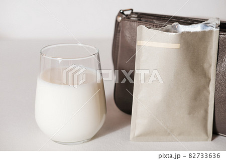 collagen powder travel pack and a glass of milk to make protein cocktail. collagen peptides powder for healthy drink. support for beautiful skin. lady's bag to take a protein sachet to go 82733636