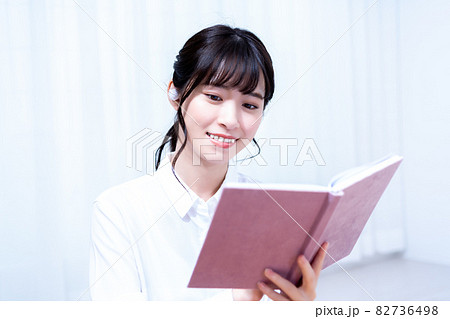 休日にリビングで音楽を聴きながら読書をする一人暮らしの若い女性 休日にリビングで音楽を聴きながら読書をする一人暮らしの若い女性 82736498