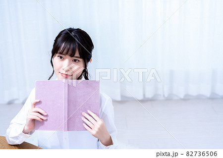 休日にリビングで音楽を聴きながら読書をする一人暮らしの若い女性 休日にリビングで音楽を聴きながら読書をする一人暮らしの若い女性 82736506
