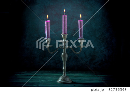 Candle magic. Purple candles in a vintage candle holder Candle magic. Purple candles in a vintage candle holder 82736543