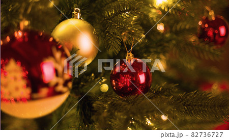 Red ball on a Christmas tree with a garland on the background of a wooden wall 82736727