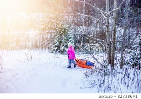 Little girl drags slide-slide cheesecake up snowy hill. Little girl drags slide-slide cheesecake up snowy hill. 82738641