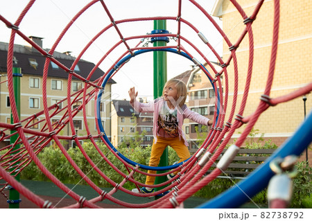 The little girl climbs ropes at the playground The little girl climbs ropes at the playground 82738792