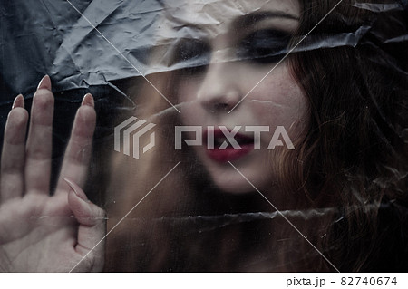 Young beauty sad woman trapped behind a plastic sheet as protection against COVID-19. Nicely fits for book cover 82740674