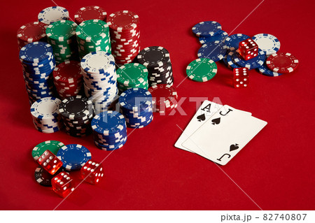 Two cards and chips on a red background. Big bet of game money. Cards - Ace and Jack. Your distribution at the table Two cards and chips on a red background. Big bet of game money. Cards - Ace and Jack. Your distribution at the table 82740807
