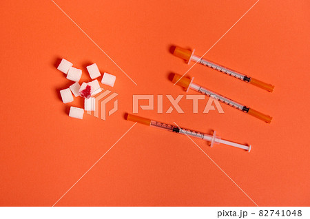 Flat lay composition of insulin syringes and white sugar cubes with blood drop isolated over colored orange background with copy space for medical ad. World diabetes day awareness concept, 14 November 82741048