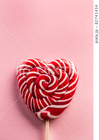Delicious looking sweet heart-like lollipop stitched on a wooden stick with rose type in background 82741434