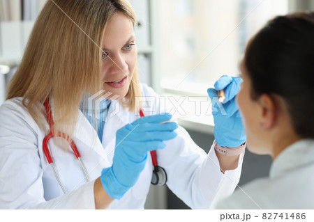 Female ENT doctor examines patient throat closeup Female ENT doctor examines patient throat closeup 82741486