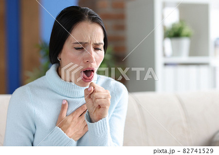 Woman with coughing fits sits on couch closeup Woman with coughing fits sits on couch closeup 82741529