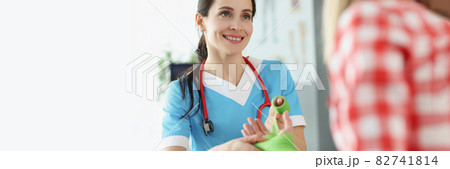 Woman traumatologist bandaging injured arm of young female patient in clinic 82741814