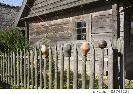 Pots for a rustic wood stove, dry on a rustic wooden palisade. Against the background of an old wooden house. 82742125