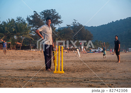 Group of Indian adults playing cricket on beach at sunset 82742306