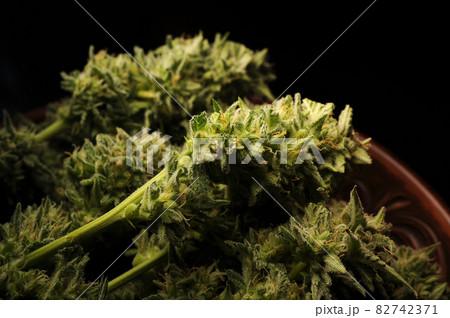 Marijuana buds in clay dish. Cannabis flowers on black background. 82742371