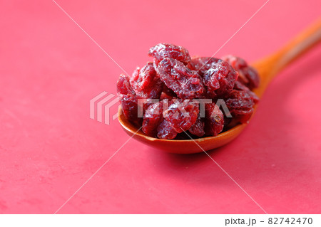 dried cranberries on a wooden spoon on red background  82742470