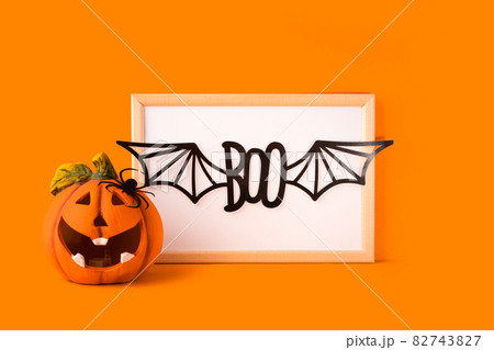 Happy halloween holiday concept. Jack o lantern, handmade paper decorations, boo text with bat wings in frame on orange background. Halloween festival party, greeting card with copy space 82743827