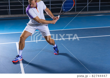 Portrait of tennis player in motion, returning a ball. Game training over court background Portrait of tennis player in motion, returning a ball. Game training over court background 82744447