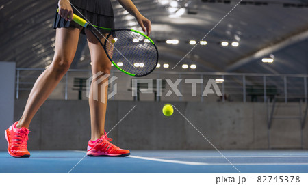 Cropped image of female tennis player in motion, legs in bright sport shoes isolated over tennis court background 82745378