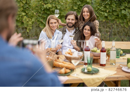 Man taking photo on smartphone of friends at picnic 82746676